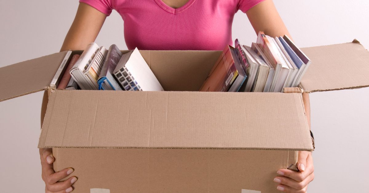 student holding a box of educational materials ready for shipping