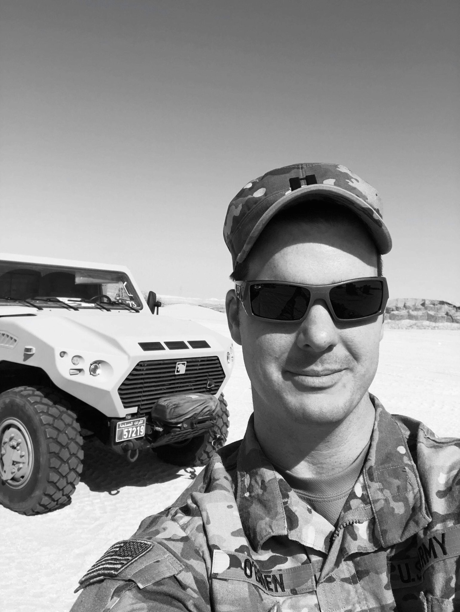service member selfie while deployed with military vehicle in background